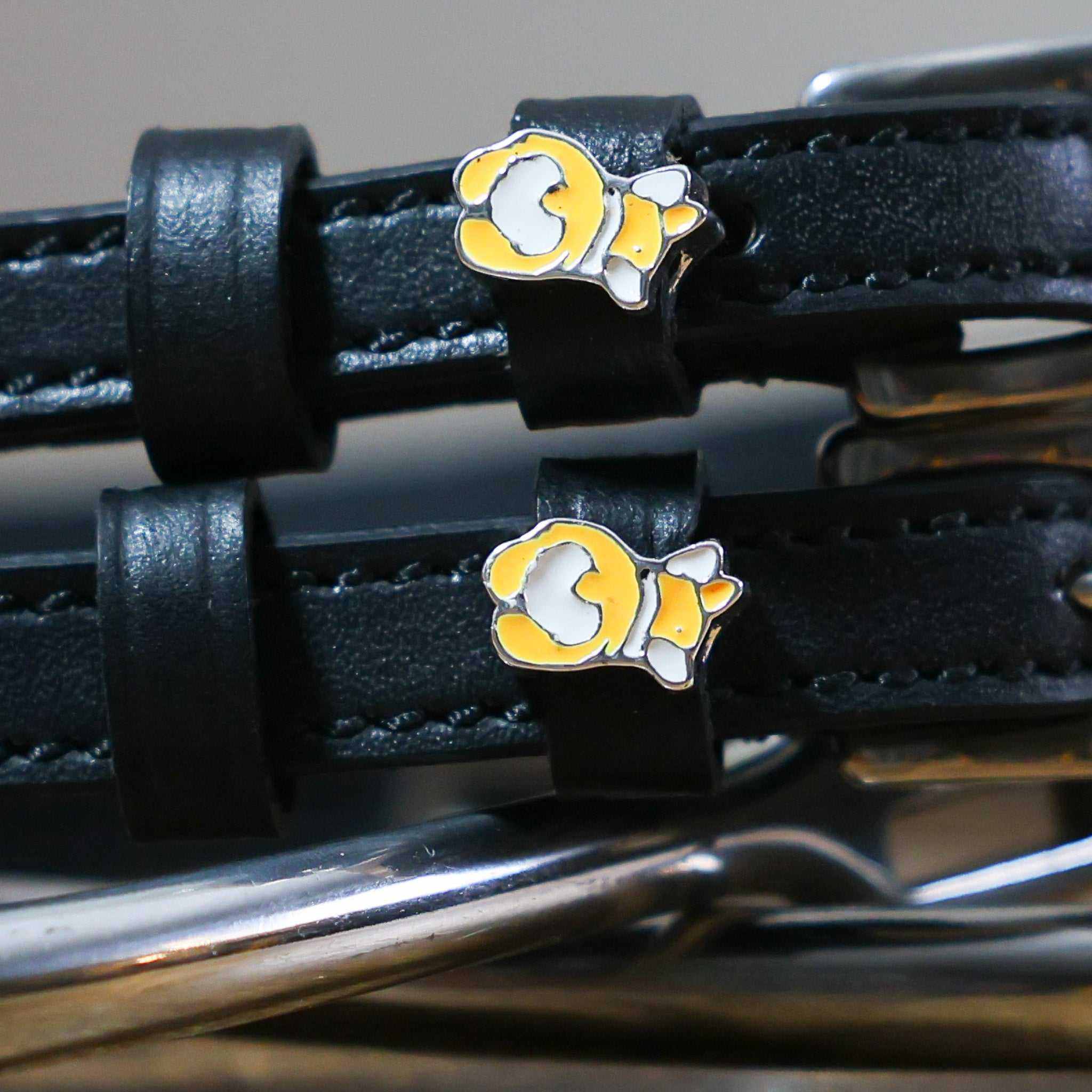 Close-up of a corgi butt charm on a black leather spur strap keeper