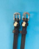 Black leather corgi butt spur straps flat-laid on a blue background