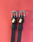 Pair of black leather corgi butt spur straps on a coral background