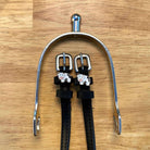 Black leather cow spur straps laid over a silver spur on a wooden surface, ManeJane cow charms
