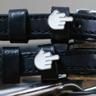 Close-up of white middle-finger emoji charms on black leather ManeJane Da Bird spur strap keepers