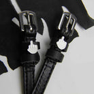 Close-up of black Da Bird spur straps and emoji charms on white with black fabric, ManeJane