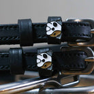 Close-up of white-and-tan bulldog head charms on black leather spur straps
