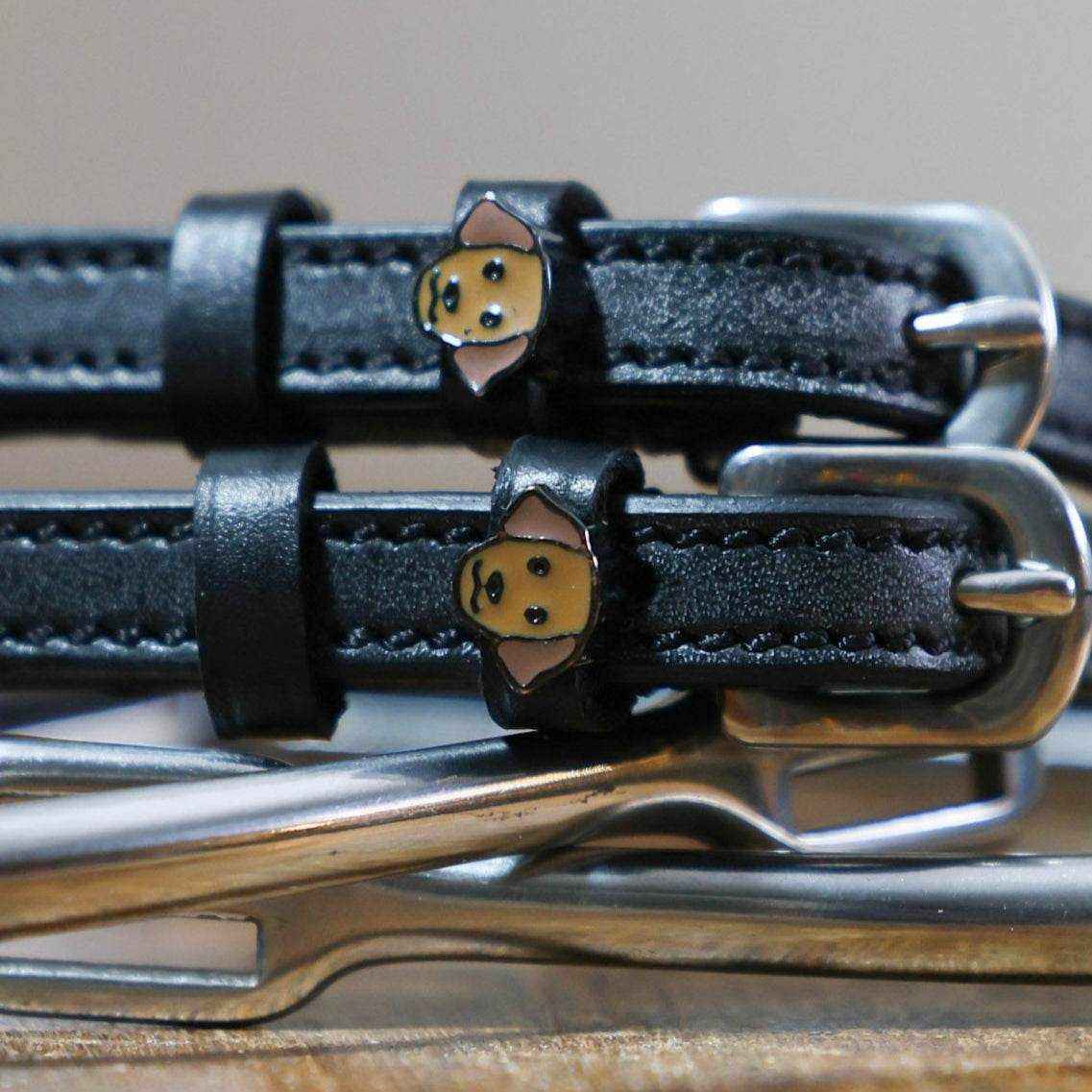 Close-up of tan Labrador dog face charms on black leather ManeJane spur straps
