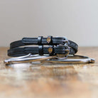 Coiled black leather Labrador spur straps resting on a silver spur, golden dog face charms