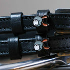 Close-up of grey donkey face charms on black leather ManeJane spur strap keepers