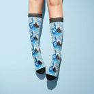 Custom socks featuring blue dreidel and Hanukkah-themed designs on light blue background worn on legs