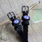 Blue evil eye spur straps resting on clear eyeglasses, ManeJane leather spur straps