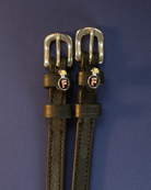 Black leather F Bomb ManeJane spur straps with silver buckles on a navy background