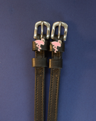 Pair of black leather flamingo spur straps flat-laid on a navy background