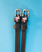 Black leather flamingo charm spur straps on a bright blue background