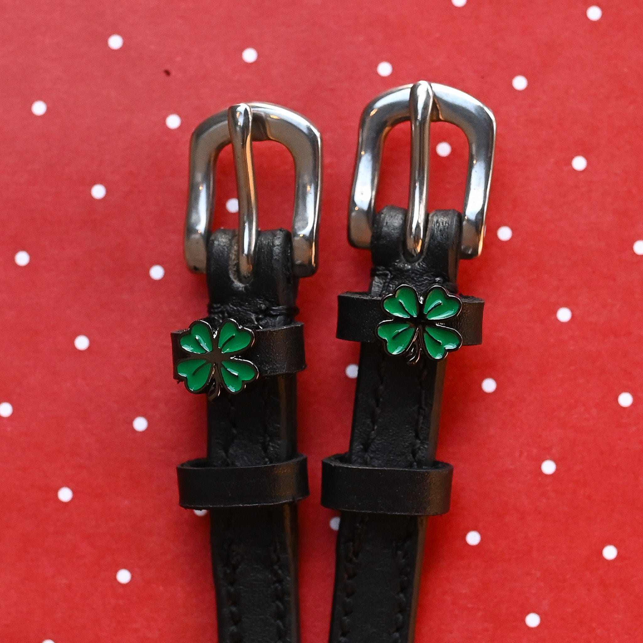 ManeJane four leaf clover spur straps with green charms on a red polka-dot background