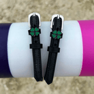 Four leaf clover spur straps draped over a purple and pink jump rail, green clover charms