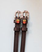 Dark brown French Fries spur straps with rose gold buckles and fry charms on pale grey