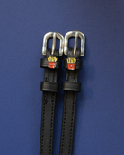 Pair of black leather French Fries spur straps with silver buckles on a navy background