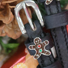 Close-up of an enamel gingerbread man charm on a black leather spur strap keeper