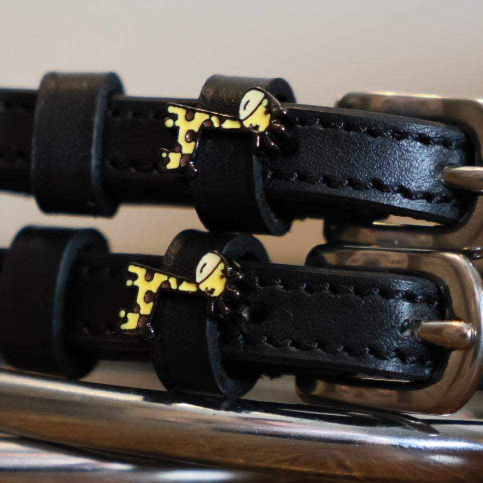 Close-up of yellow giraffe charms on black leather spur straps over spur hardware