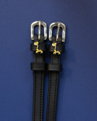 Pair of black leather Giraffe spur straps with silver buckles on a navy background