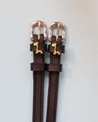 Dark brown Giraffe spur straps with rose gold buckles and giraffe charms on pale grey