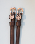 Brown leather ManeJane spur straps with rose gold buckles and rhinestone clover charms
