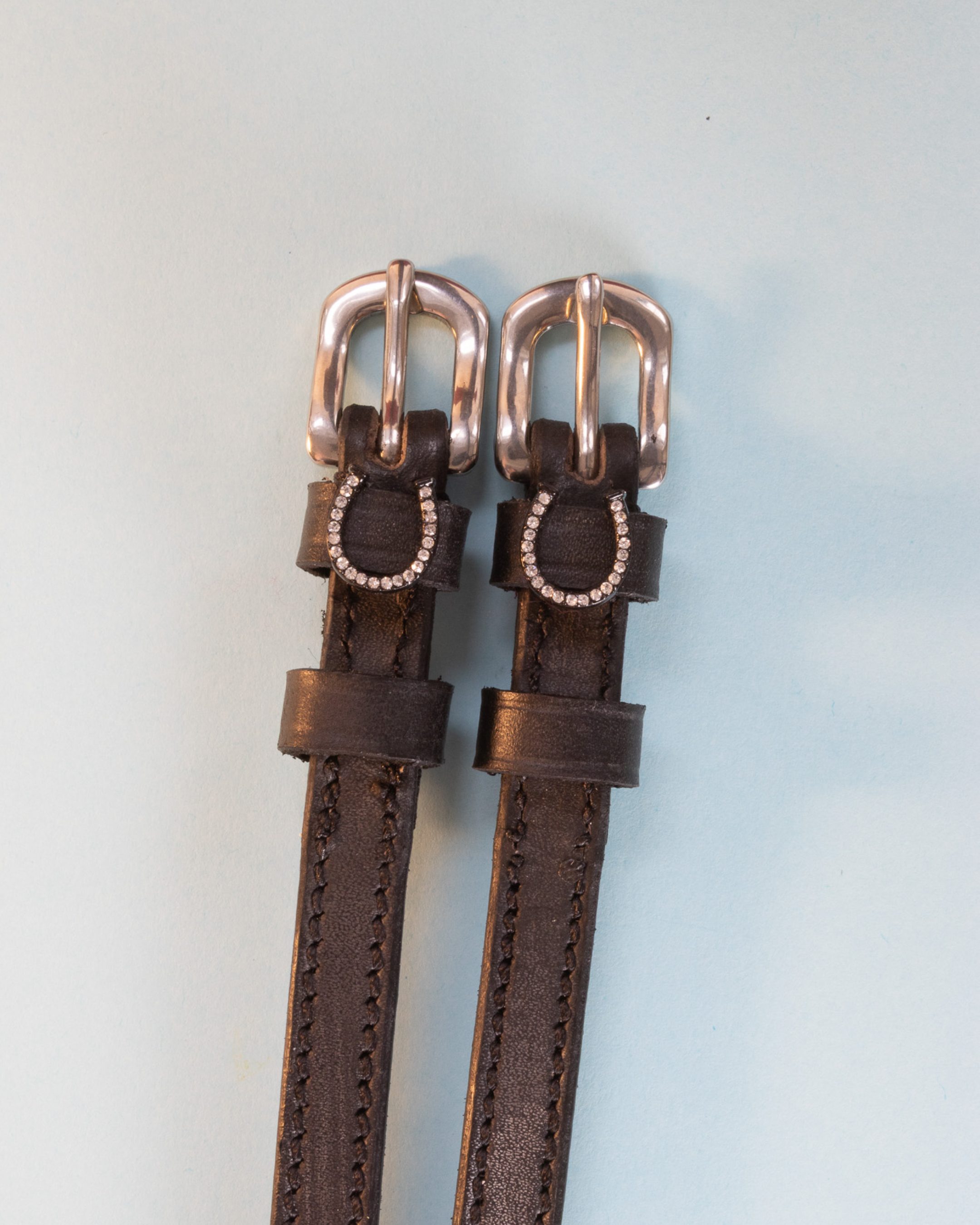 Brown leather spur straps with rose-gold buckles and crystal horseshoe charms