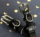 Angled close-up of crystal horseshoe spur straps on a starry moon-print backdrop