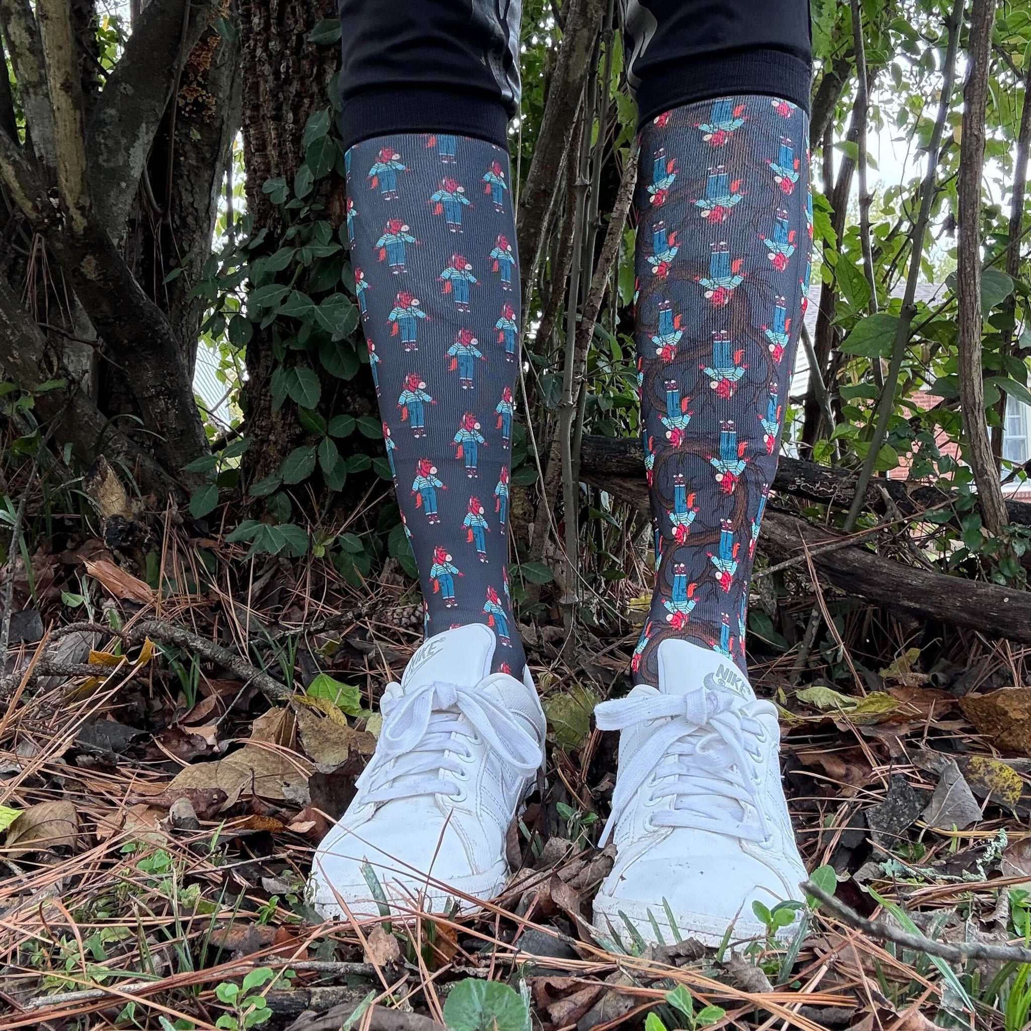 Limited Edition Trotting Up That Hill boot socks with colorful figure pattern worn with white sneakers outdoors