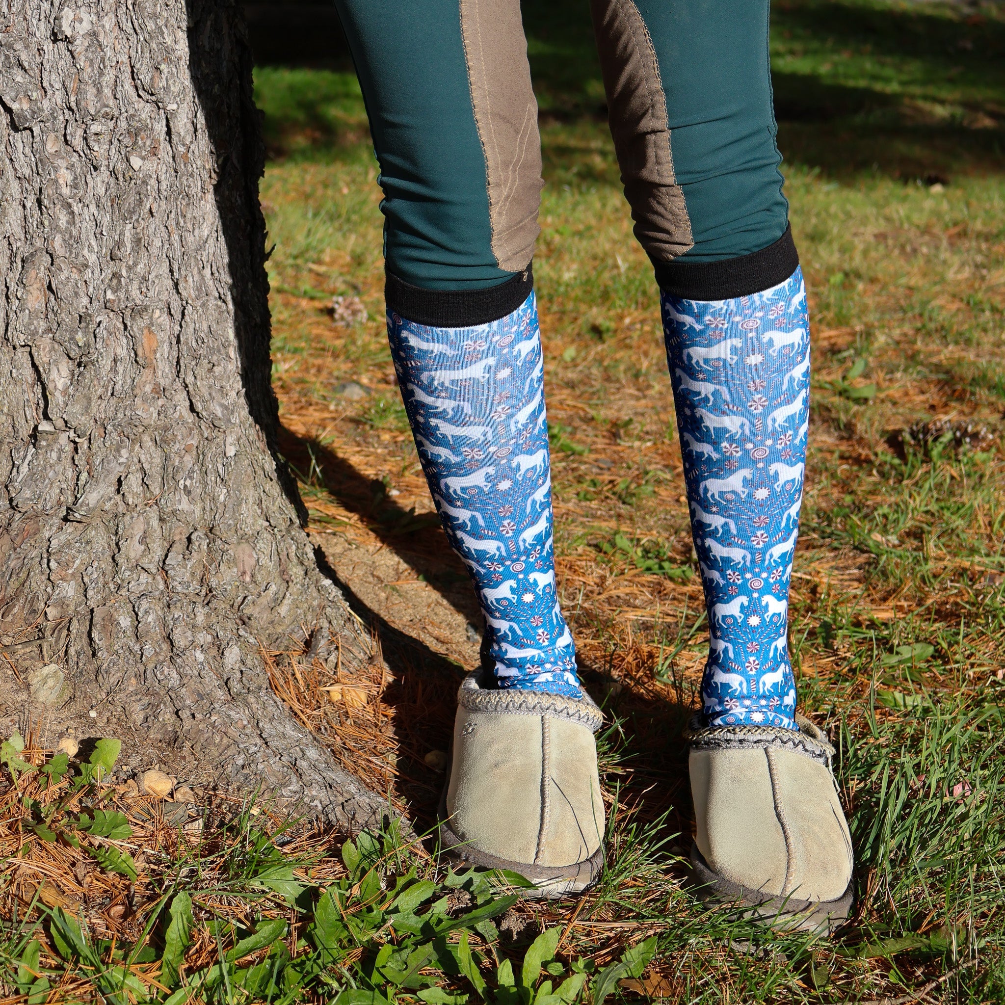 Limited Edition Pony Island Peppermint Ponies socks blue with white pony and candy cane pattern worn with slippers outdoors