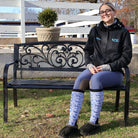 woman sitting on bench wearing Limited Edition Pony Island Dala Horses Socks with blue and white folk-art pony design