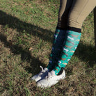 Limited Edition Pony Island green boot socks with horse pattern worn with riding pants and white sneakers outdoors