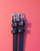 Black leather ManeJane spur straps with ice cream cone charms on a coral background