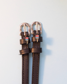 Dark brown leather ManeJane ice cream cone spur straps with silver buckles on grey