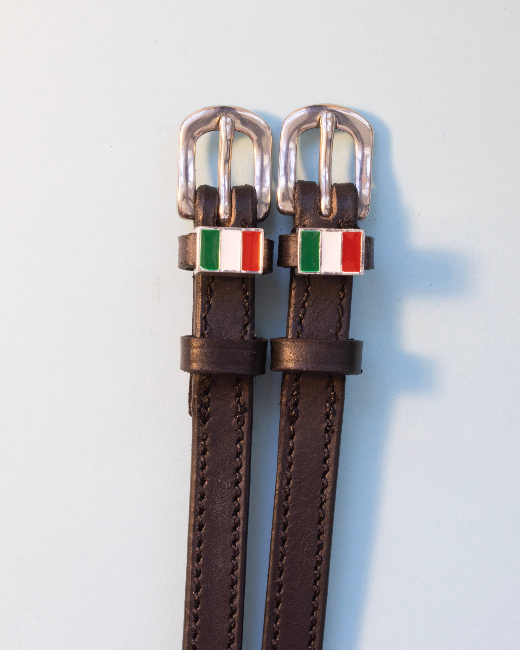Pair of brown leather ManeJane spur straps with Italian flag charms on grey