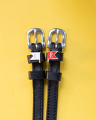 Black leather jump-flag spur straps with L and R charms on a yellow background