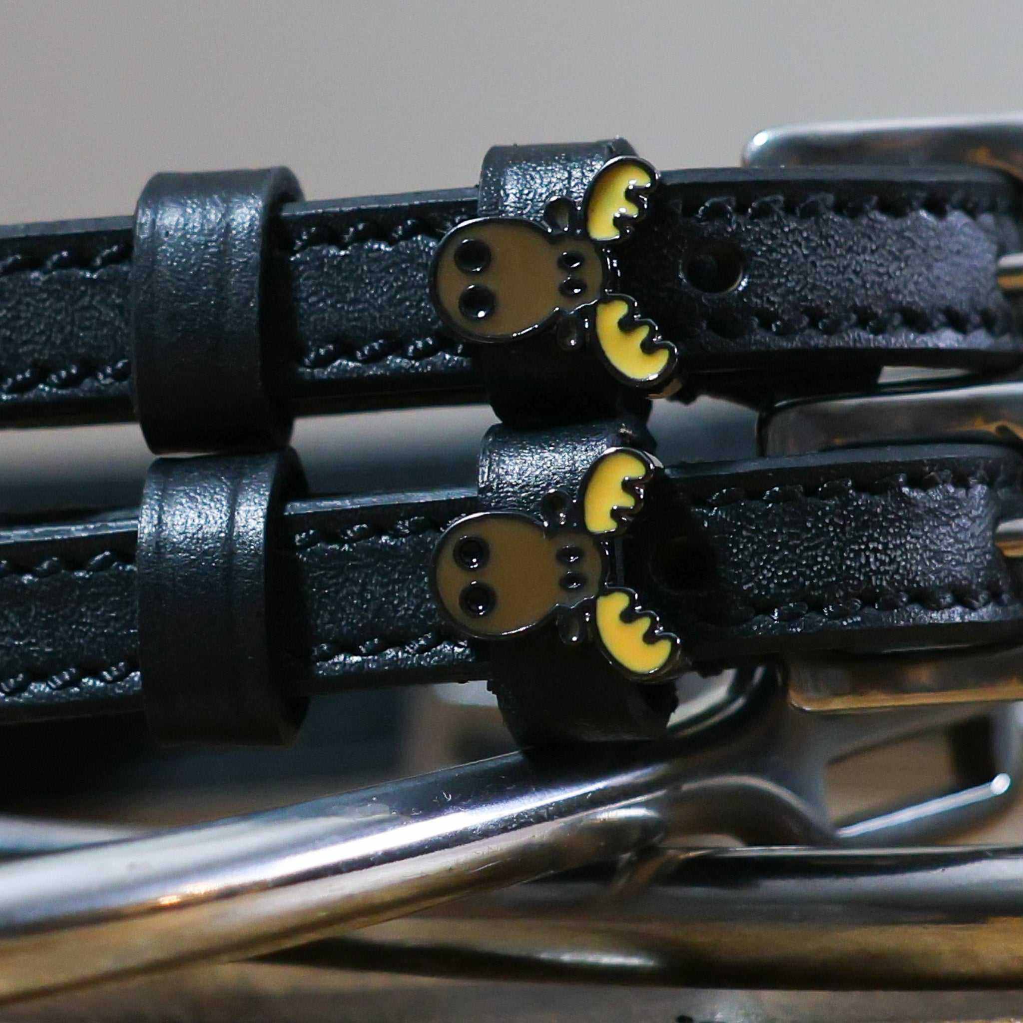 Close-up of brown moose head charms on black leather spur strap keepers