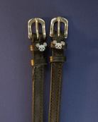 Black leather ManeJane Mouse spur straps with silver buckles on a navy background