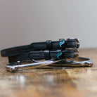 Nice Dino spur straps coiled beside a stirrup on a wooden tabletop