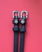 Black leather rhinestone owl spur straps with silver buckles on a red background