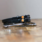 Black leather peach spur straps coiled beside a silver spur on wood