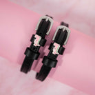 Pink dinosaur charm spur straps with silver buckles on a pink marbled background