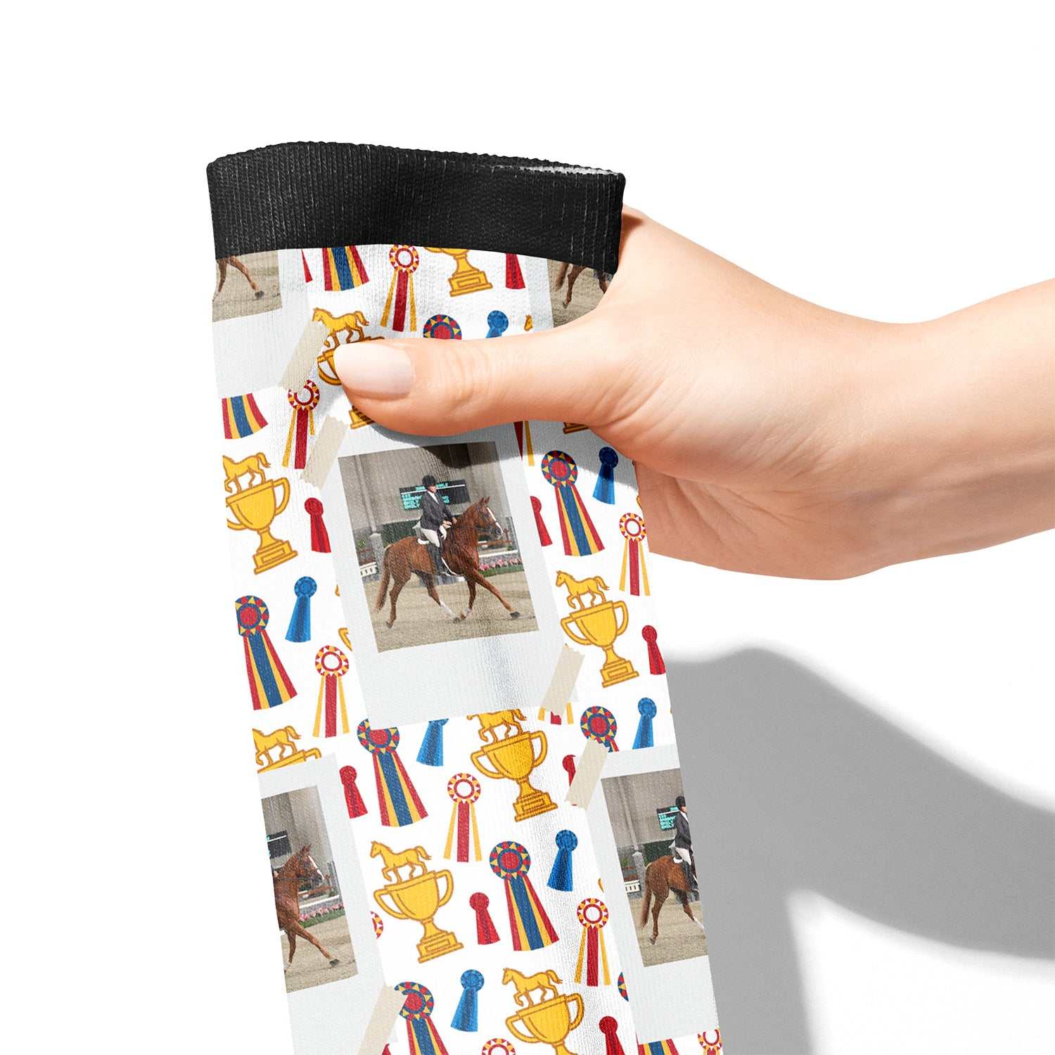 Hand holding custom boot socks with horse, trophy, and ribbon design pattern