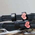 Detail of pink Pony Love heart charms on black leather ManeJane spur straps