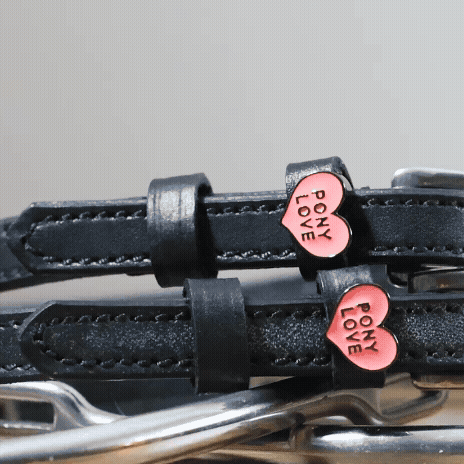 Detail of pink Pony Love heart charms on black leather ManeJane spur straps