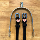 Pony Love spur straps hung from a silver spur bracket on a wood surface