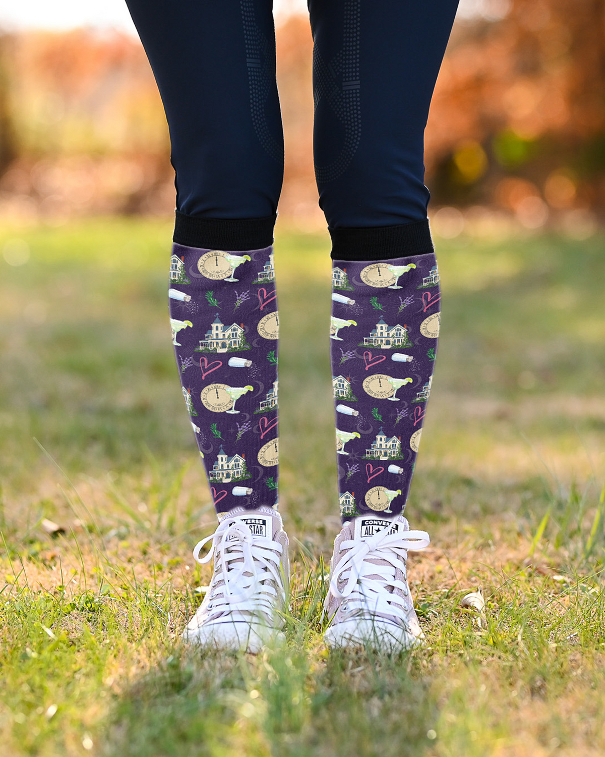 Midnight Margaritas boot socks worn over navy breeches with white sneakers, purple print showing at the calf