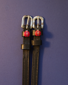 Red ladybug ManeJane spur straps laid flat on a navy background