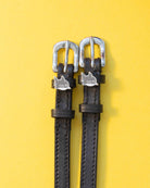 Black leather ManeJane shark charm spur straps with silver buckles on yellow