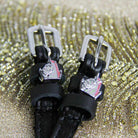 Close-up of silver unicorn charms on black leather spur straps against gold glitter