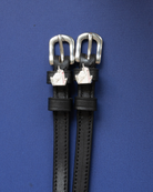 ManeJane unicorn charm spur straps with silver buckles flat-laid on deep blue