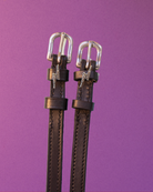Rhinestone lightning bolt spur straps on brown leather against a purple background